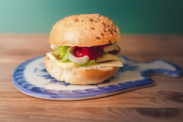 Homemade hamburger with fresh vegetables on Gzhel cutting board