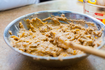 Savory Scone Batter with Shredded Cheddar Cheese in a Steel Bowl with a Wooden Spoon