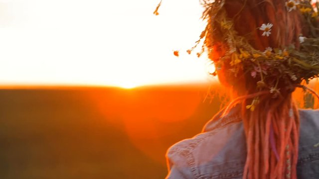 Woman walks through the field. Girl is going through the wildflowers and touching with the grass and flowers. Girl during sunset. Going into the sunset. Flowers in the field. Girl in the field