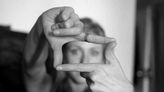 Womans hands coming into focus framing a shot. Black and white.