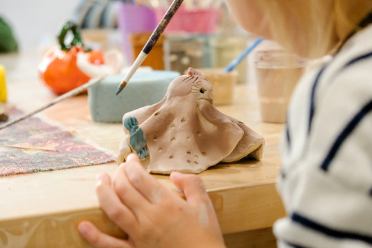 A child paints his clay figurine in a workshop at a modeling lesson.