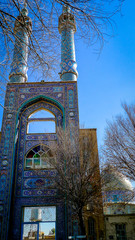 Blue tiled portal of the Hazireh Mosque in Yazd, Iran, surrounded by bare winter branches