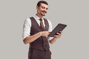 Handsome young arabic businessman in brown suit holds tablet