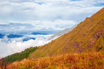 landscape - view from the mountain pass on a sunny day to the valley hidden by low clouds