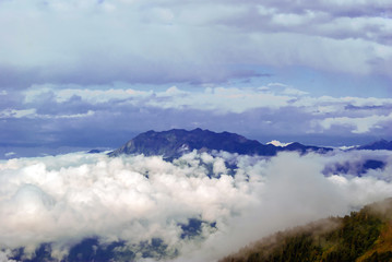 landscape - view from the mountain pass on a sunny day to the valley hidden by low clouds