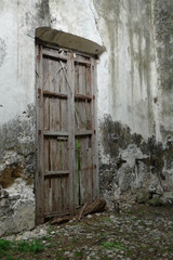 Rustic old wooden door on a concrete jungle wall in colonial Mexico. 