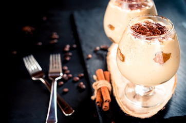 tiramisu in a glass decorated with coffee beans on a dark background