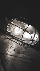 Fototapeta na wymiar Light bulb in metal case on tiles in car mechanic workshop. Black and white
