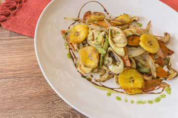 White plate with sauteed vegetables on wooden background