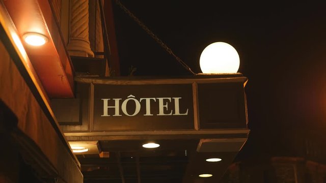 Hotel sign in Ville de Quebec, Quebec, Canada. Insects flying around lights. Wide shot.