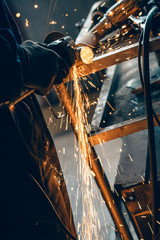Close up of car mechanic hands welding grinding machine.Sparks of grinding machine while cutting...