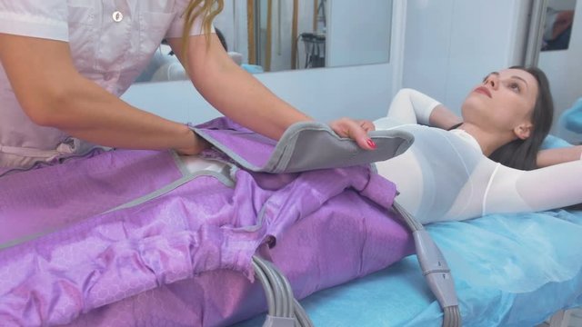 Woman at the clinic for the treatment of pressure therapy procedure. Preparing to procedure with a doctor.