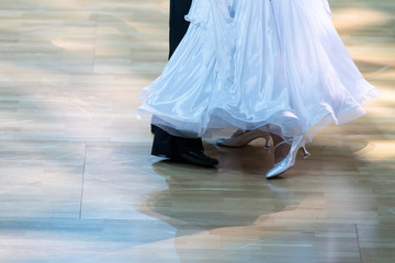 Fototapeta na wymiar Closeup of Feet and Legs of Professional Ballroom Dance Couple Prior to Performing Youth Standard Program on Dancefloor.