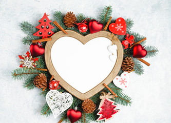 Fototapeta na wymiar Christmas frame in the shape of a heart is surrounded by branches of a New Year tree Christmas decorations with copy space. Top view, flat lay. Nature New Year concept.