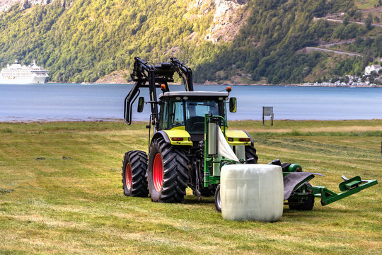 Small Tractor With A Round Bale Wrapper On A Field In Geiranger, Norway.