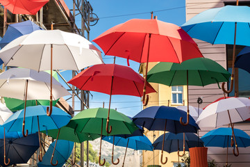 Fototapeta na wymiar A group of umbrellas hanging on wires multicolored outside on the street.