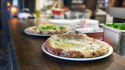 Closeup of pizza margherita placed on a white plate at the kitchen ready to be served.