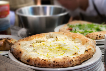 Closeup of pizza margherita placed on a white plate at the kitchen ready to be served.