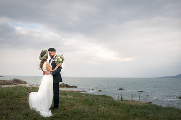 young couple bride groom getting married wedding posed photos at seaside sea beach hairpiece flowers bouquet church