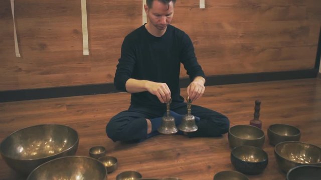 A man sits in a lotus position with bells
