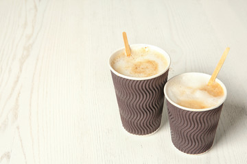 Cardboard cups of coffee on wooden background. Space for text