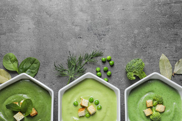 Flat lay composition with different fresh vegetable detox soups made of green peas, broccoli and spinach in dishes on table. Space for text