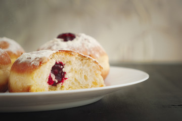 Tradition Jewish holiday sweets, donut sufganioyt with sugar powder and jam close up on plate with copy space.
