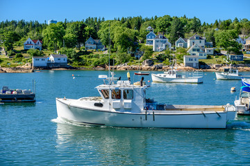 Fototapeta na wymiar Maine Lobster Boats Anchored in a Bay in Front of a Quaint New England Village