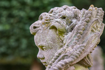 Stone angel statue in garden. Guardian angel statue in sunlight as a symbol of love in garden.