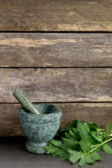 Fresh Valerian Herb Leaves  with Green Marble Mortar and Pestle with rustic wooden background on slate