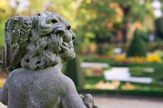 Stone angel statue in garden. Guardian angel statue in sunlight as a symbol of love in garden.