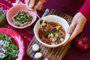 Woman hands holds hot traditional beetroot, cabbage red soup - borsch for lunch or dinner. Red New Year background. Vegan and vegetarian. Happy Christmas food