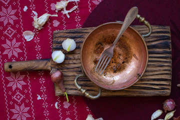 Unclean dirty dishes left after finished food process - breakfast, lunch or dinner. With traces of sauces or pieces of food on surface. Messy kitchenware. Christmas tablecloth. Copper pan