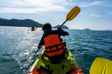 Asian teenagers paddling on green and red kayaks