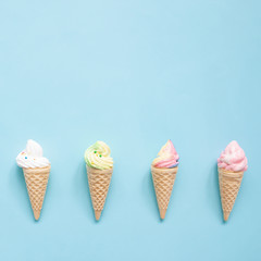 Pastel meringue on ice cream cones on blue background