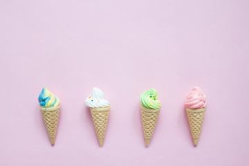 Pastel meringue on ice cream cones on pink background