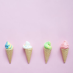 Pastel meringue on ice cream cones on pink background