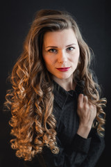 Portrait of a young woman with curly hair in a black shirt