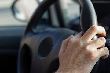 Male driver holding steering wheel while driving