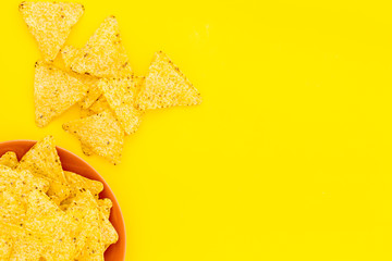 Naklejka premium Mexican snack. Make nachos. Crispy nachos on plate on yellow background top view copy space