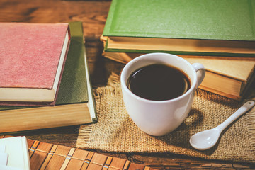 cup of coffee among books on a wooden table.