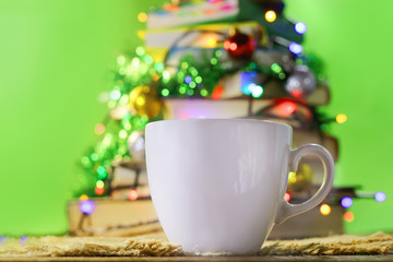 cup of coffee on a blurred background a stack of books in the Christmas decorations.