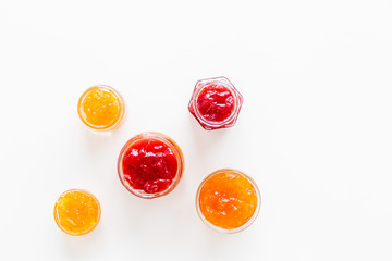 Set of sweet jams in glass jars on white background top view copy space