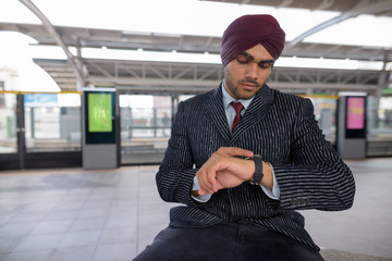 Indian businessman checking time from smart watch at train station
