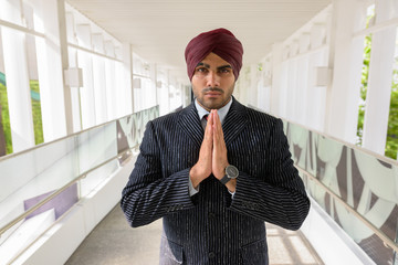 Portrait of Indian businessman with turban greeting outdoors in city