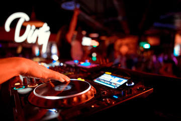 DJ turntable console mixer controlling with two hand in concert nightclub stage.