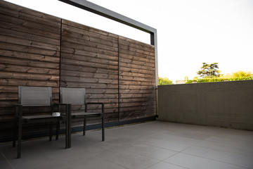 Home terrace or balcony with cozy metal chair for relaxing with wooden brick wall.