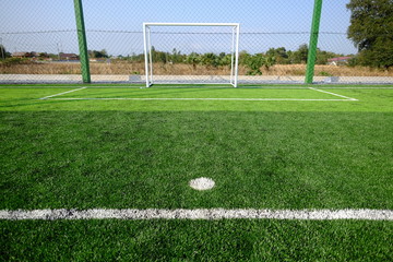 Soccer football on green grass field and goal post