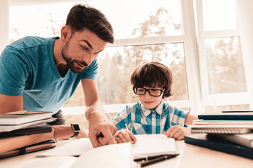 Little Boy in Glasses Doing Homework with Father.