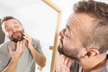 Fototapeta premium Man looking at beard in mirror